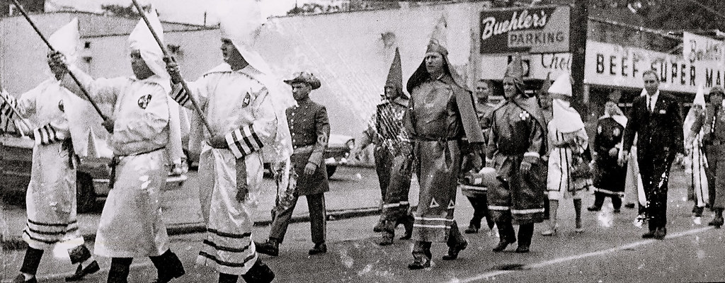 Black and white image of men wearing elaborate uniforms with pointed hats and robes.