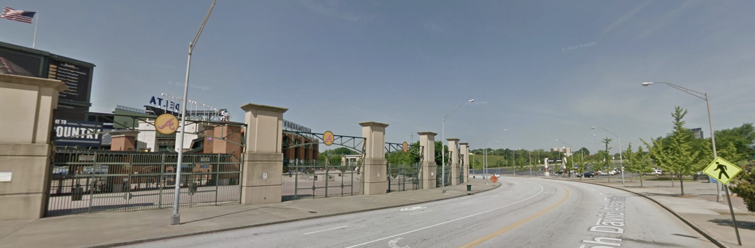 The Atlanta Braves stadium gate dominates the left side of an image showing a road with cars driving on it.