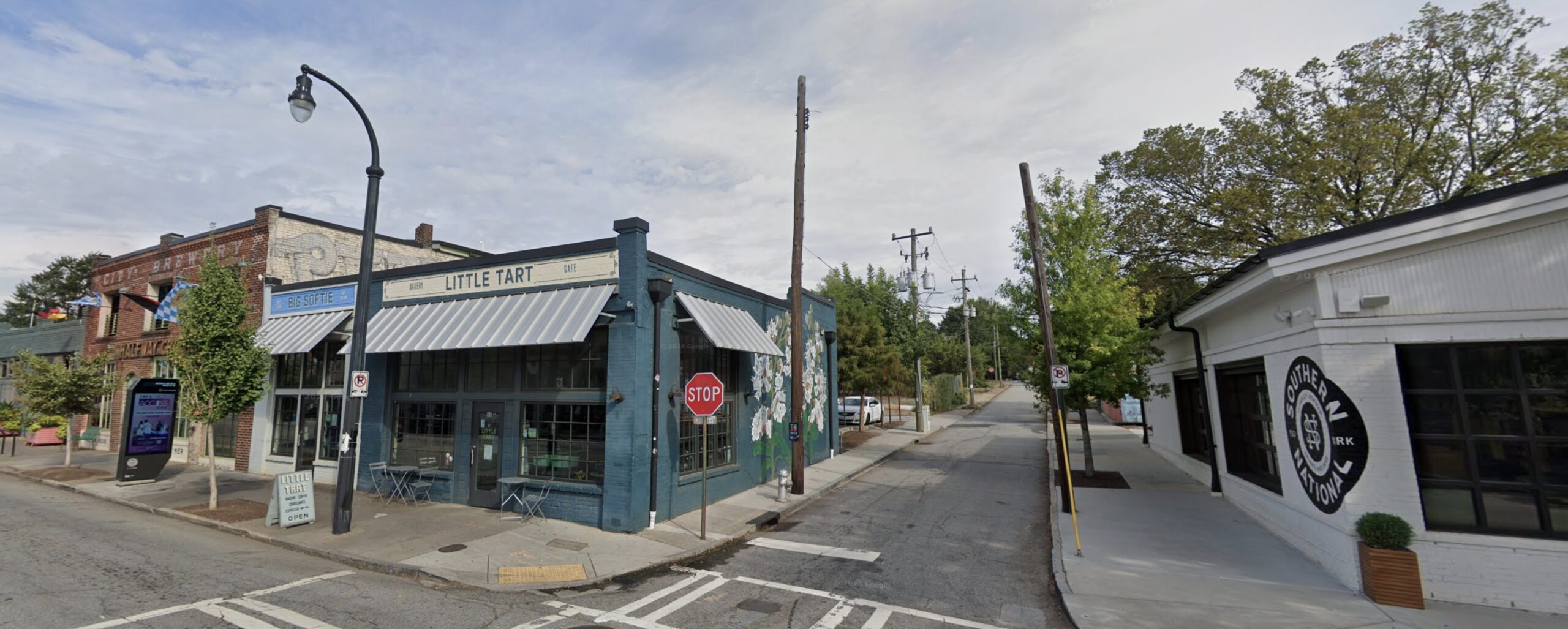 Color photo of a street corner with recently-painted store fronts occupied by businesses.