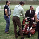 image of four men, one sitting on a WSB branded lawnmower 