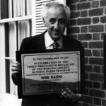 black and white image of a man holding a plaque commemorating the 3,000th WSB radio broadcast of the Sunday Worship Service from First Presbyterian Church of Atlanta