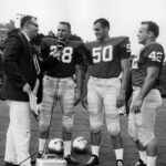 black and white image of three college football players with a WSB radio reporter