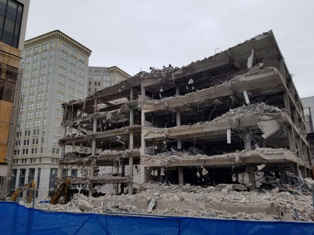 Color photograph of the demolition of Kell Hall showing a building that has been partly demolished with floors open for view and debris scattered on the ground in front